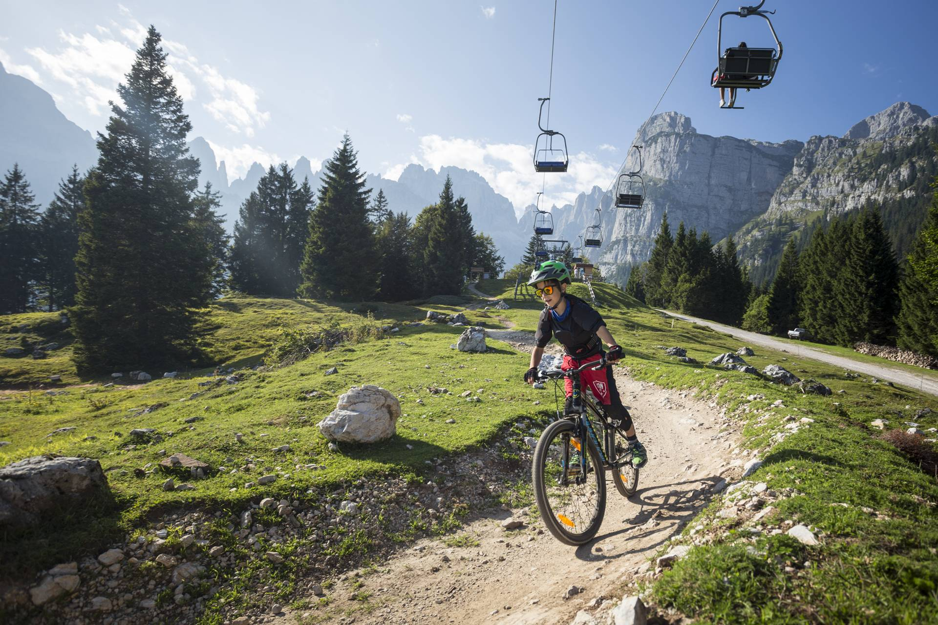 Un bambino scende lungo il trail Big Hero sull'altopiano di Pradel, sopra a Molveno con le Dolomiti di Brenta alla spalle. | © Filippo Frizzera, 2017