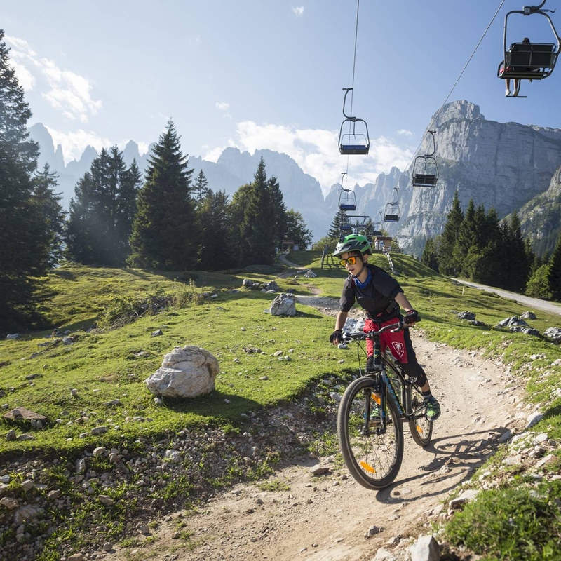 Un bambino scende lungo il trail Big Hero sull'altopiano di Pradel, sopra a Molveno con le Dolomiti di Brenta alla spalle. | © Filippo Frizzera, 2017