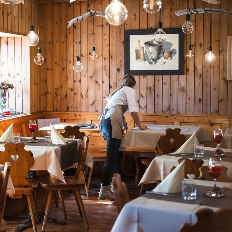 Una ristoratrice è impegnata nella preparazione della sala ristorante prima dell'apertura. | © Frame & Work, 2024