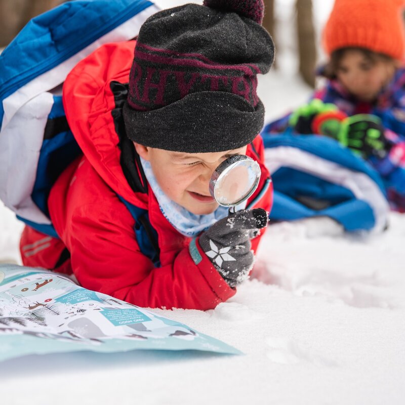 Bambini usano mappa e lente di ingrandimento per scoprire la natura innevata in Paganella. | © Oliver Astrologo, 2020