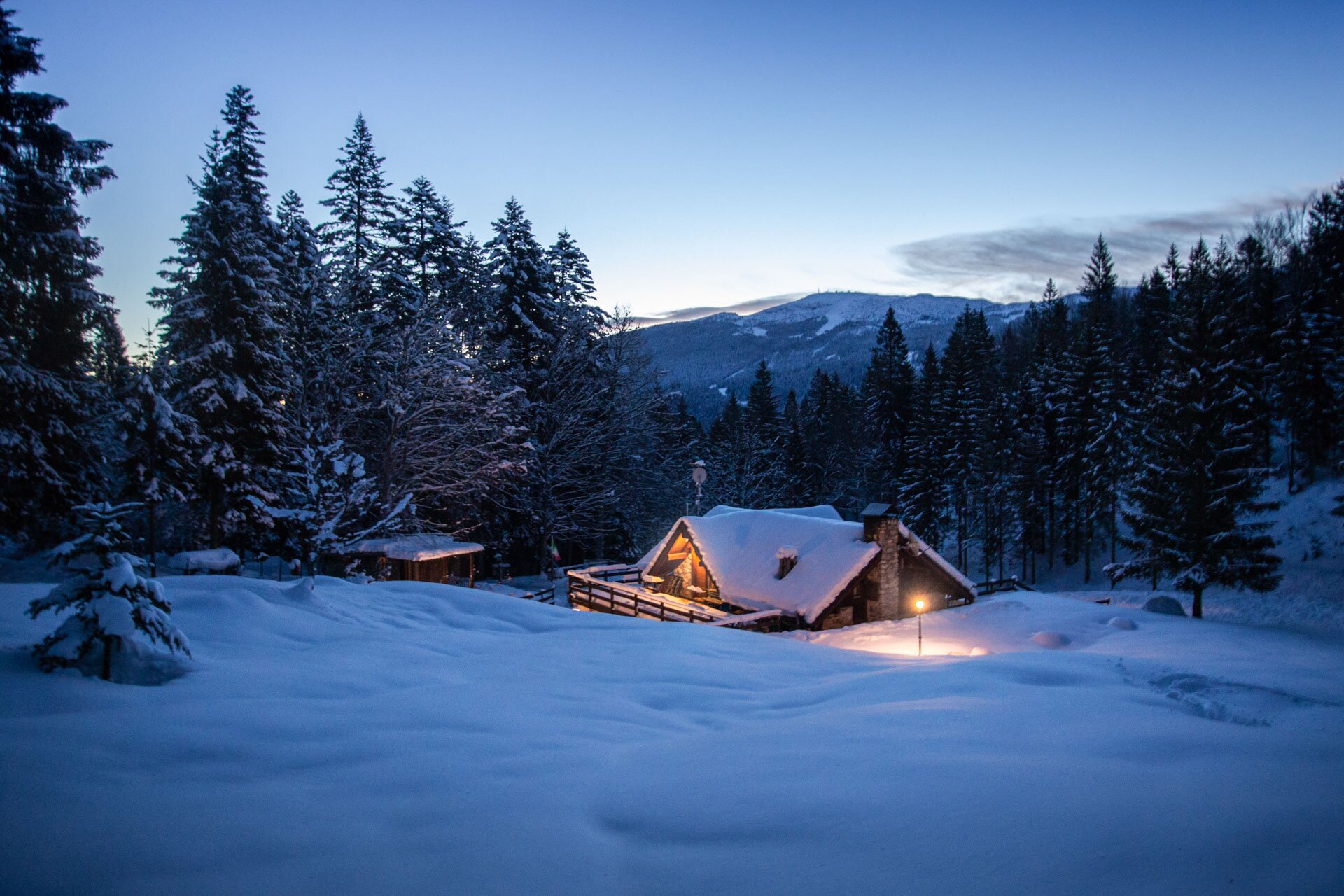 Pineta chalet surrounded by snow during the evening. Inside lights on for dinner. | © Filippo Frizzera, 2019