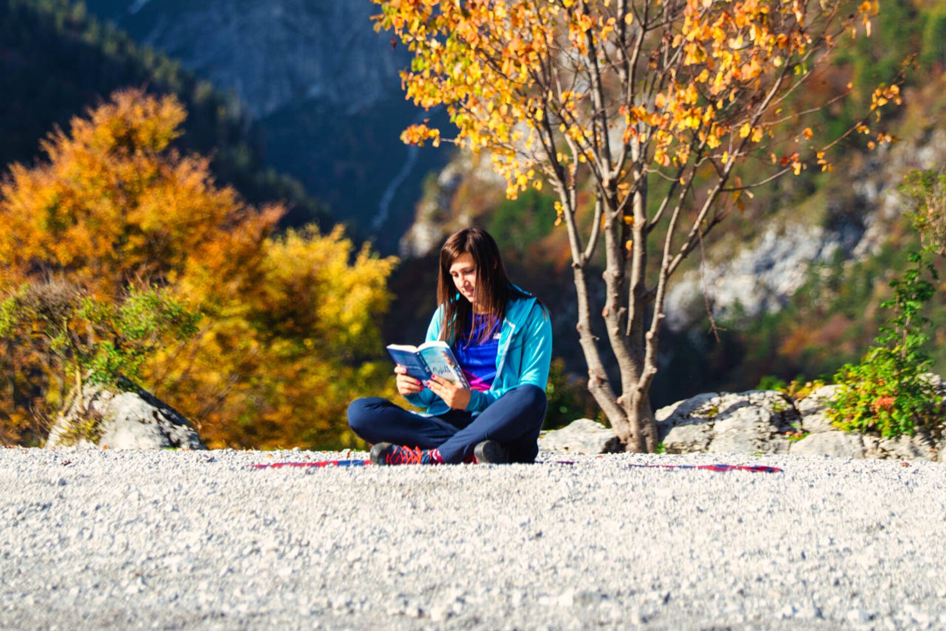 Mädchen sitzt am Ufer des Molvenosees mit den Brenta-Dolomiten im Hintergrund und liest ein Buch | © Filippo Frizzera, 2020