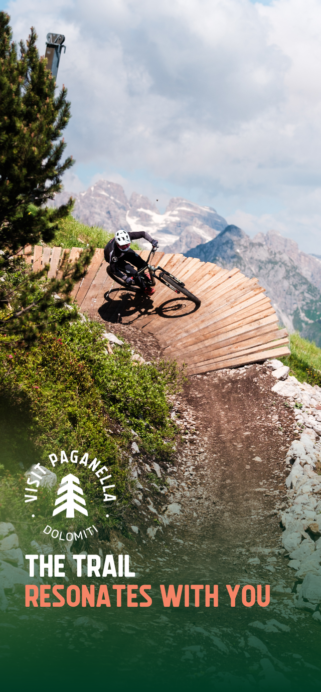 In the picture: a biker on a wallride with a view of the Brenta Dolomites behind him. In the text: The trail resonates with you. | © Filippo Frizzera, 2024