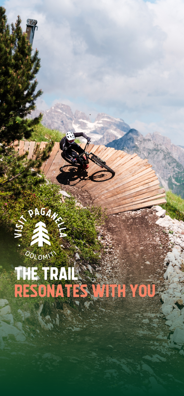 In the picture: a biker on a wallride with a view of the Brenta Dolomites behind him. In the text: The trail resonates with you. | © Filippo Frizzera, 2024