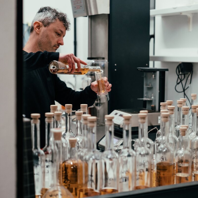 Lab technician works with whiskey test tubes to find the right flavor | © Frame & Work, 2024